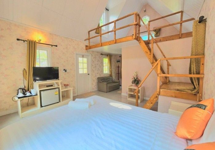 A hotel room with a bed , television , stairs and a balcony.