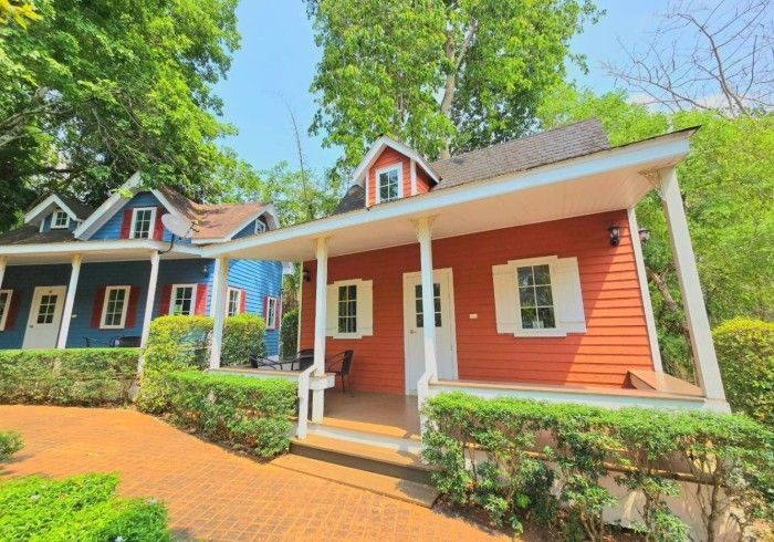A red house with a white porch is next to a blue house.