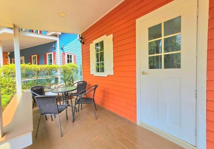 There is a table and chairs on the porch of a house.