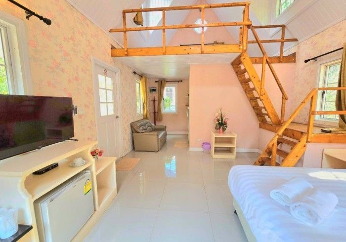 A bedroom with a bed , television , stairs and a balcony.