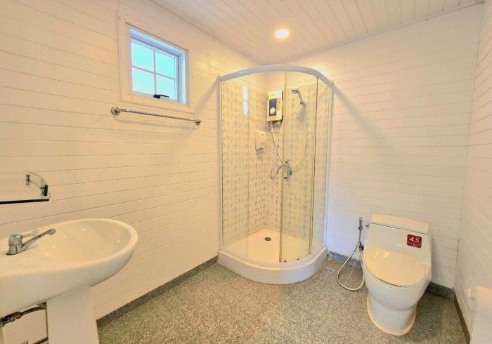 A bathroom with a toilet , sink , shower and window.