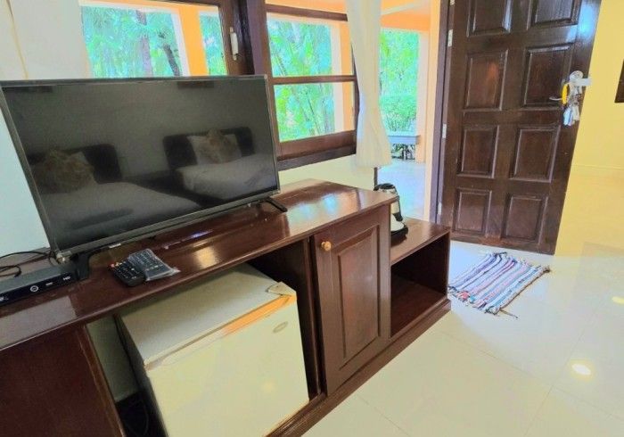 A hotel room with a flat screen tv and a refrigerator