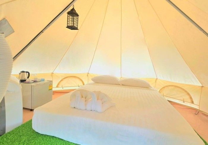 A bed in a tent with a lantern hanging from the ceiling.