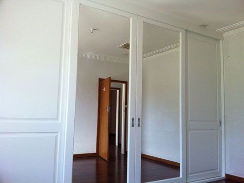 combination sliding vinyl wrap and mirror doors reflecting open brown door