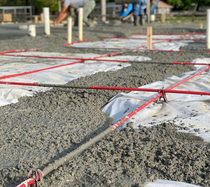 A construction worker is spreading concrete with a trowel.