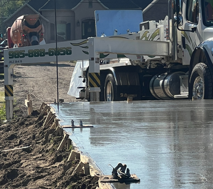 A man is pouring concrete into a hole with a shovel.