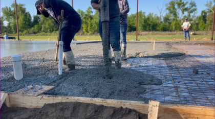 A group of construction workers are working on a concrete floor.