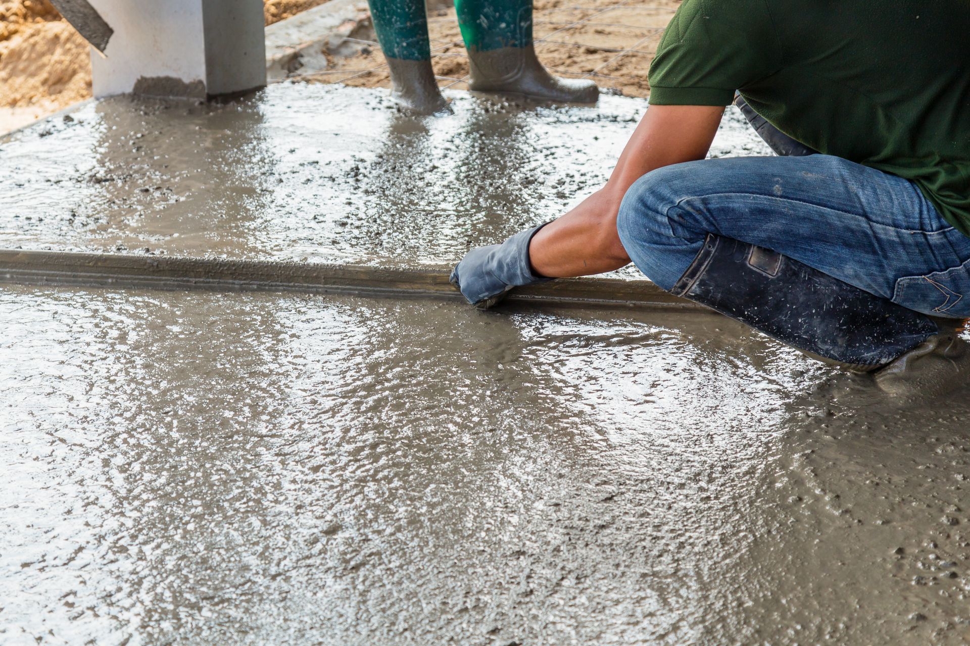 A man is kneeling down on a concrete floor.