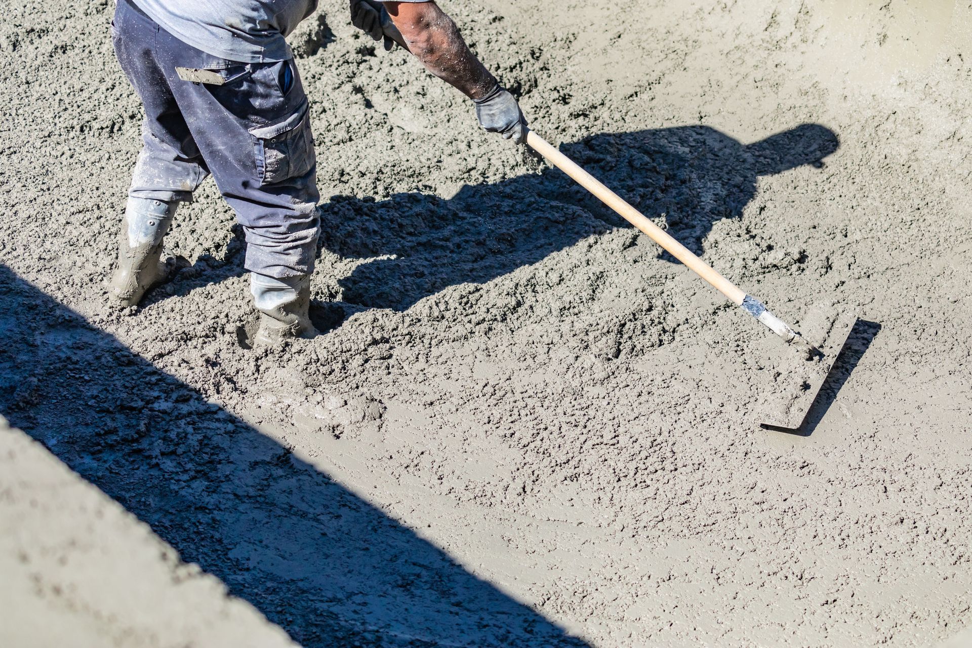 A man is raking concrete with a rake.