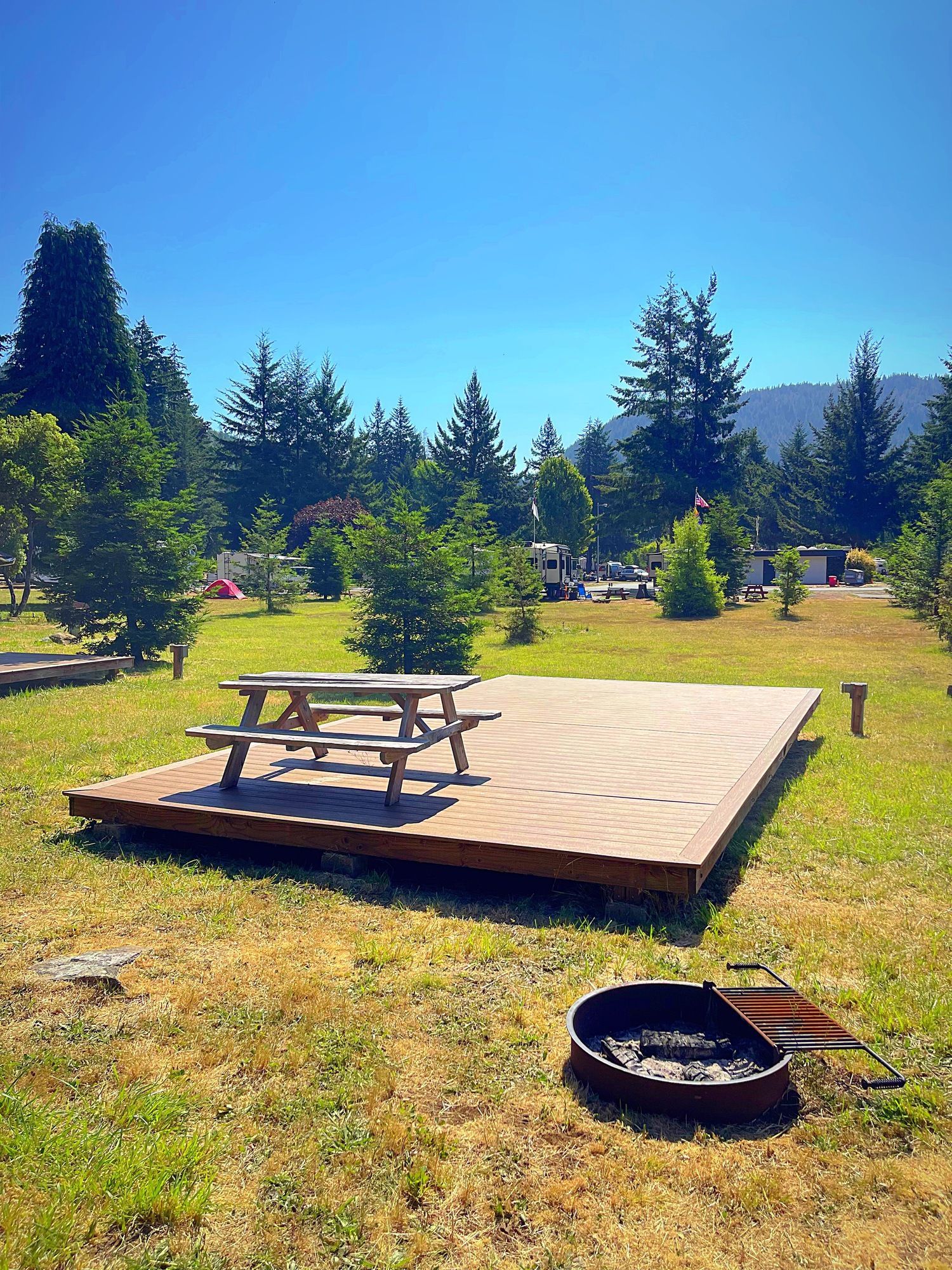 A picnic table is sitting on top of a wooden platform in a grassy field.