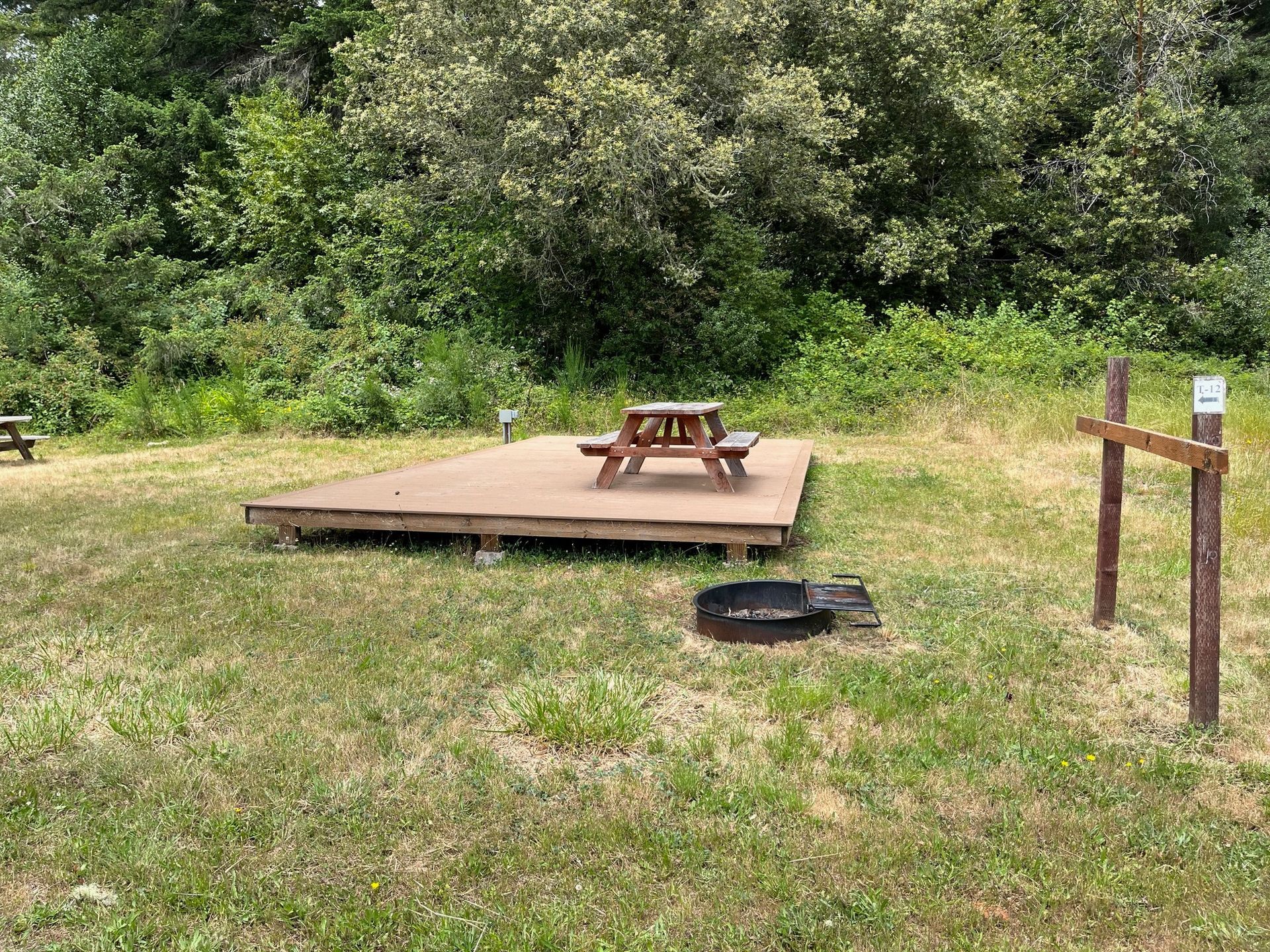 A picnic table is sitting on a wooden platform in the middle of a grassy field.