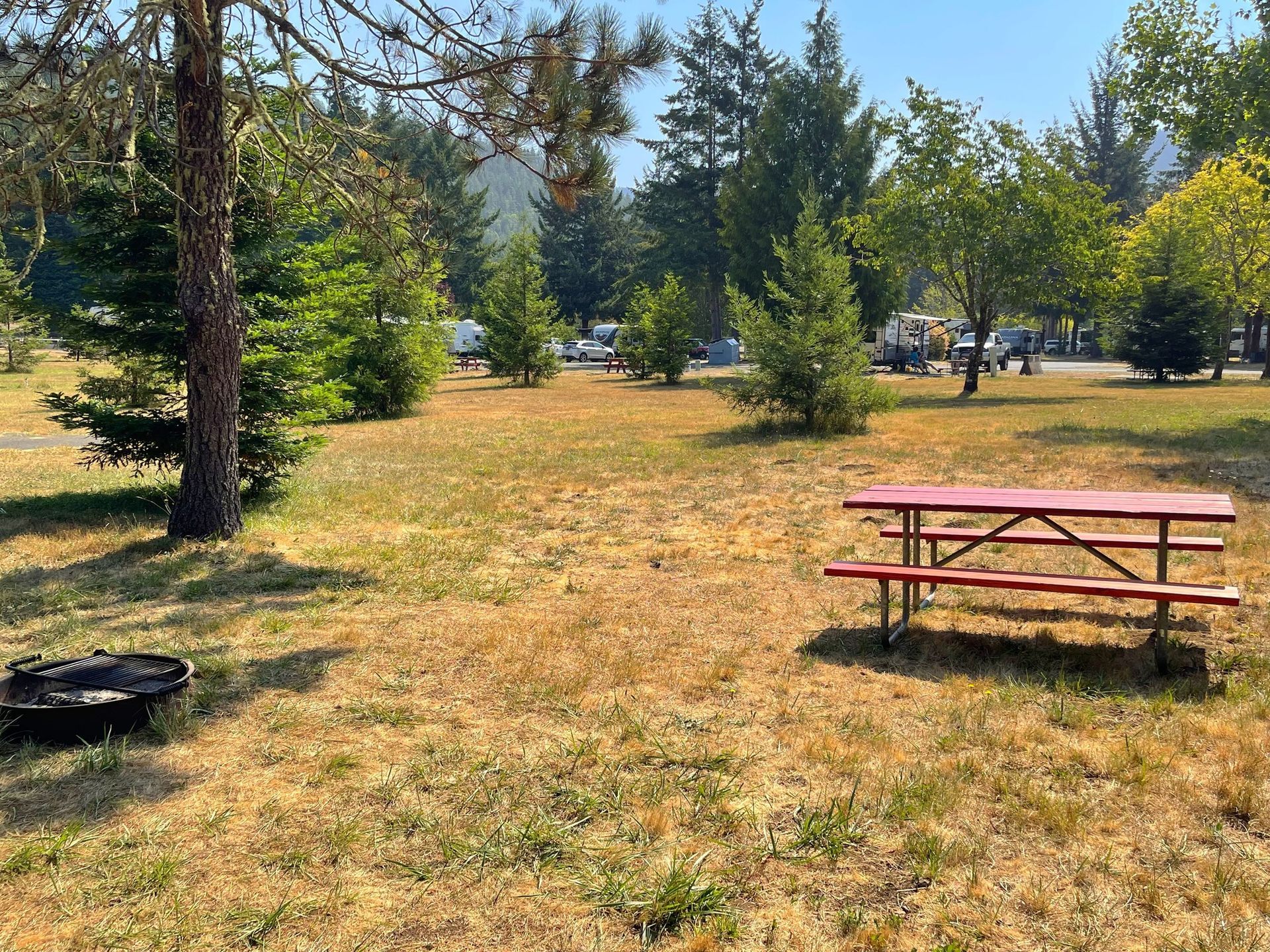 A red picnic table is sitting in the middle of a grassy field.
