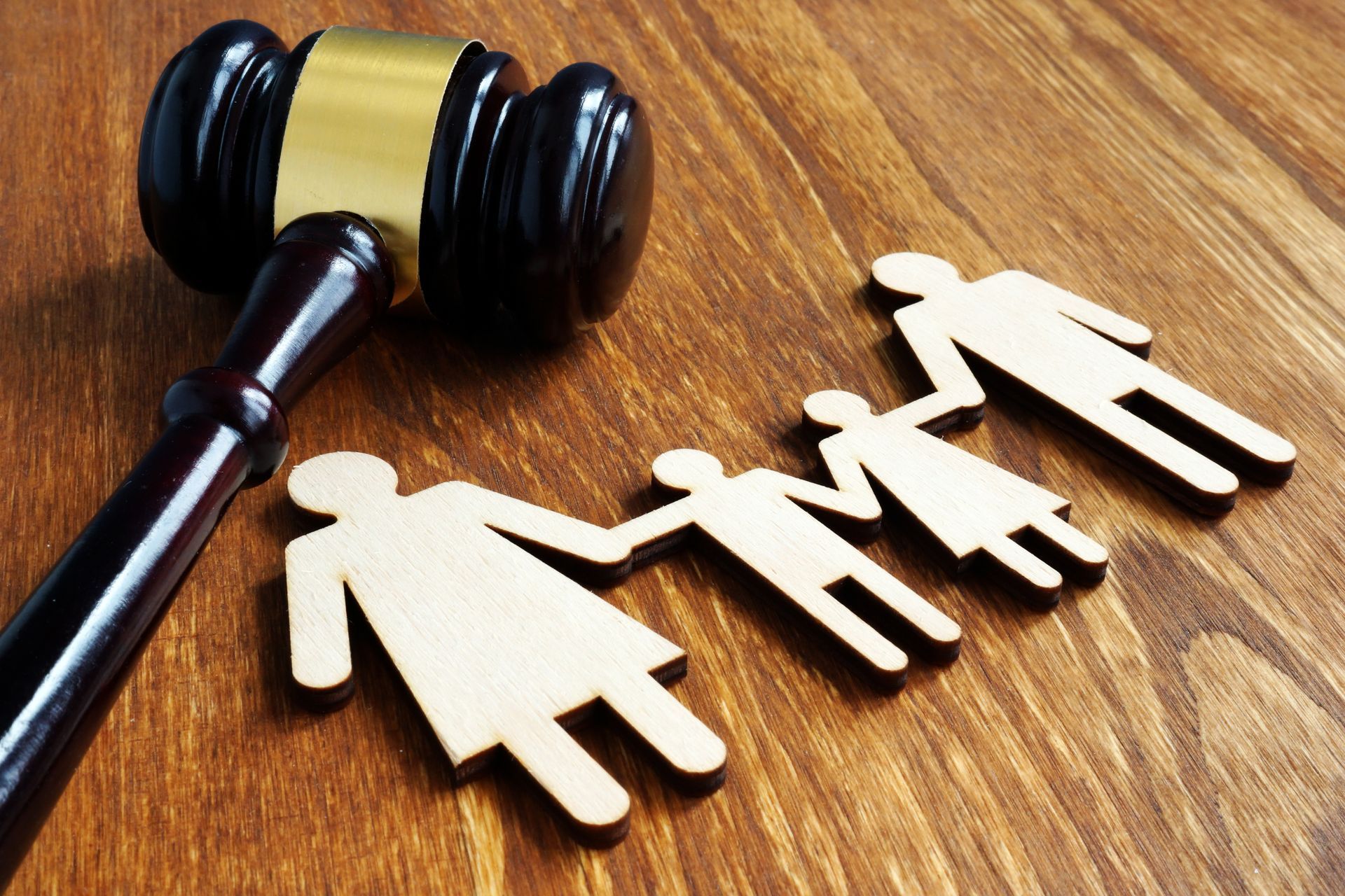 Gavel next to wooden family cutouts on a wooden surface, suggesting a family law or custody case.