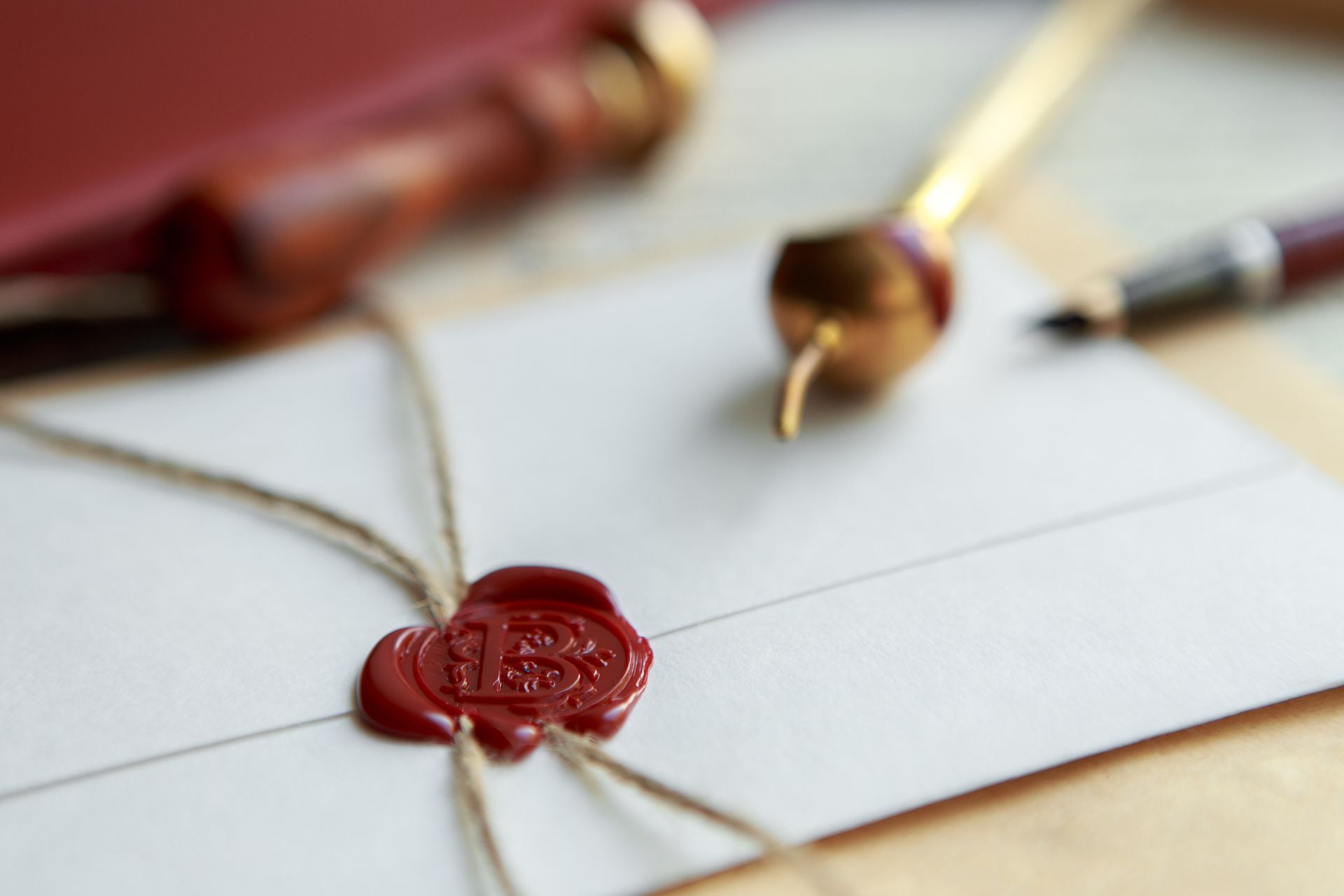 Envelope sealed with red wax, twine, with stamp and pen on the side.
