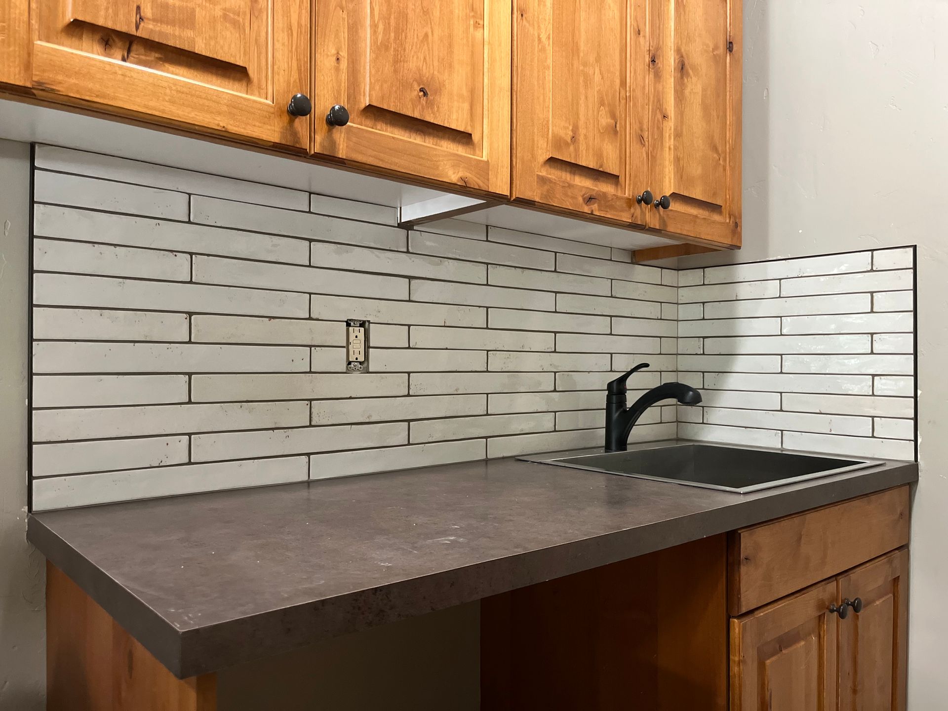 A kitchen counter with a sink and wooden cabinets
