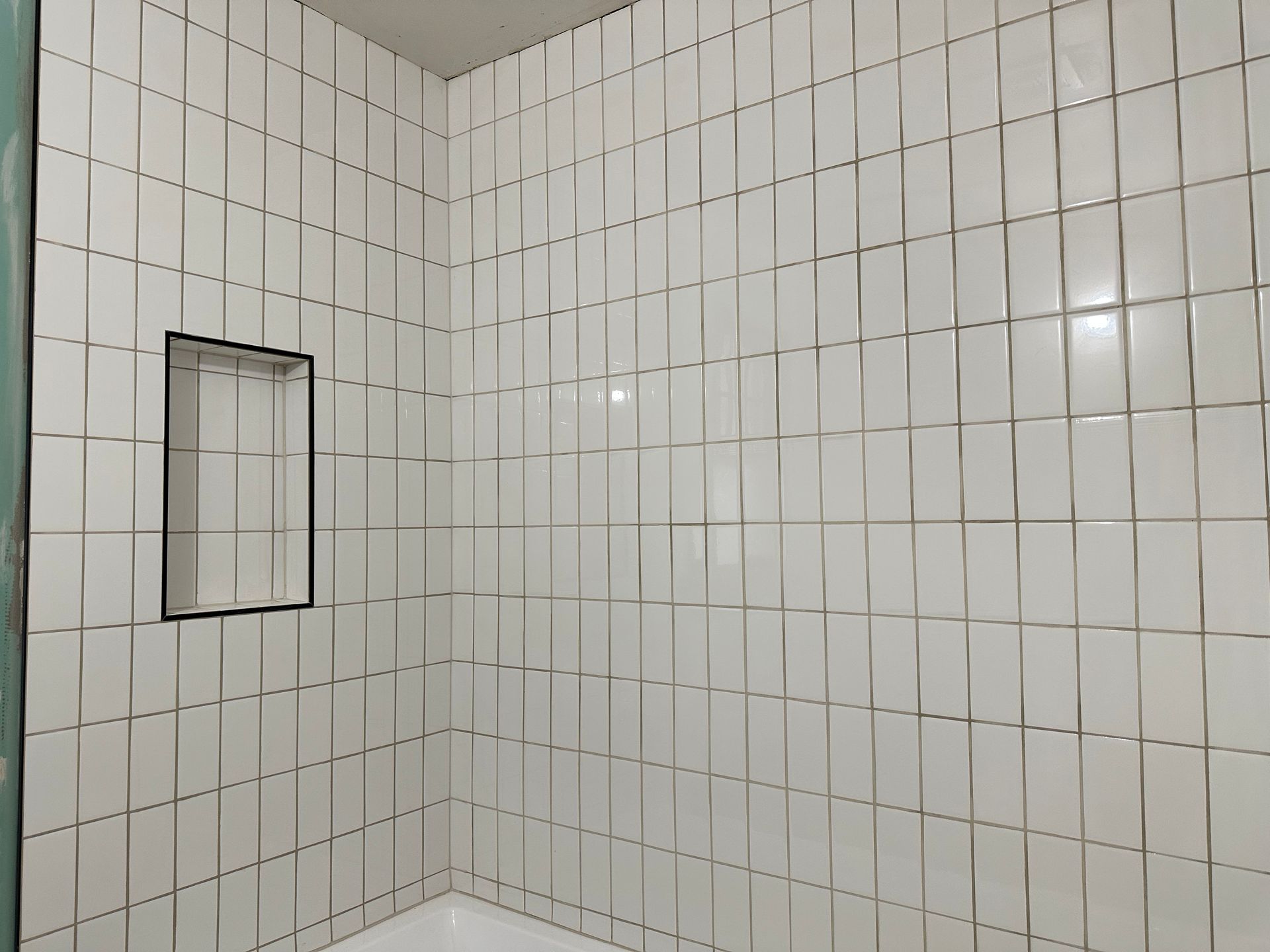 A bathroom with white tiles and a bathtub