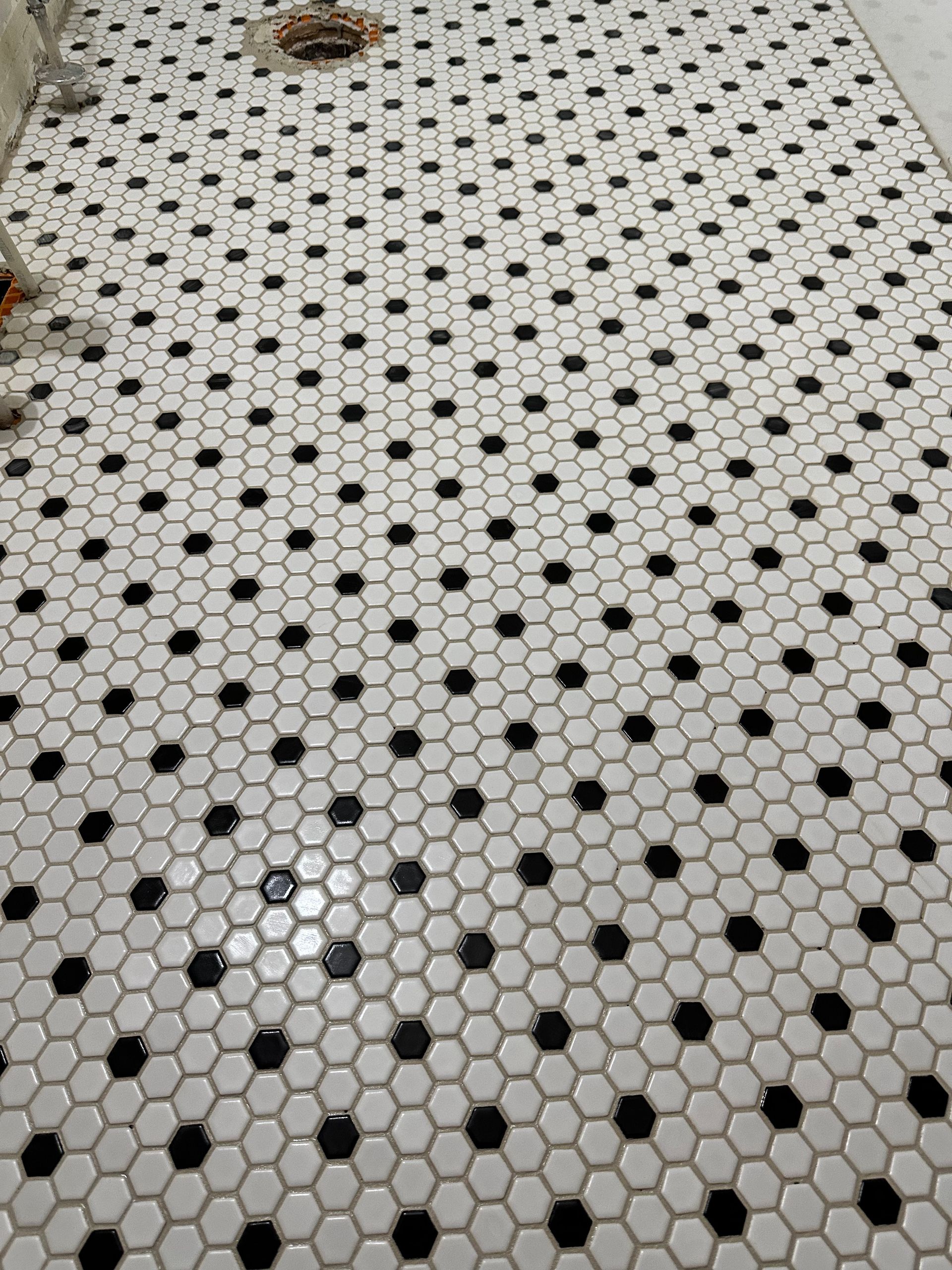 A bathroom floor with black and white hexagon tiles.