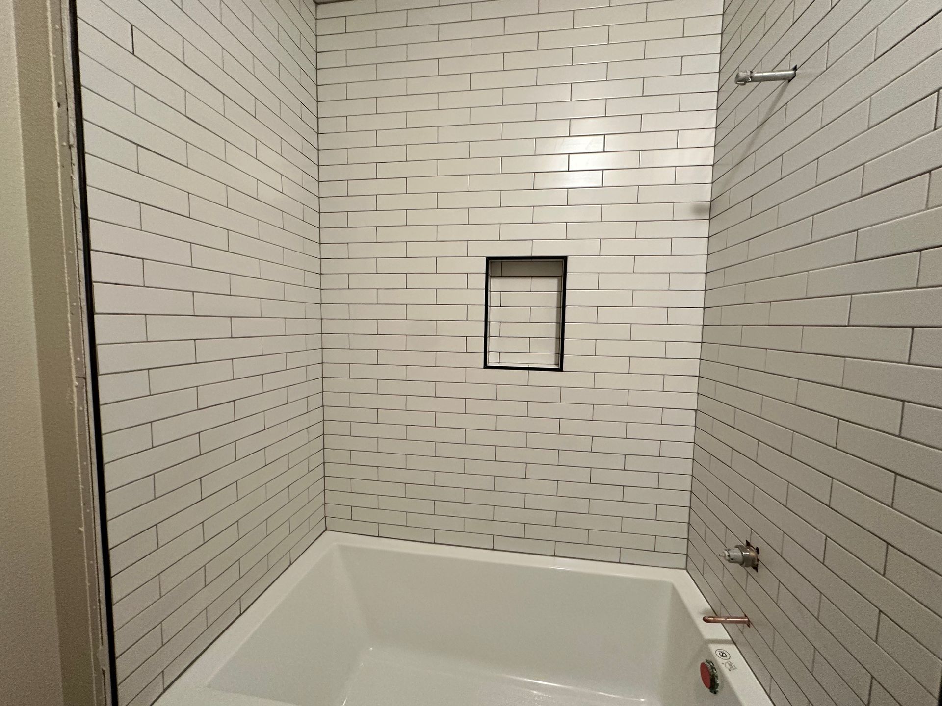A bathroom with white brick walls and a bathtub