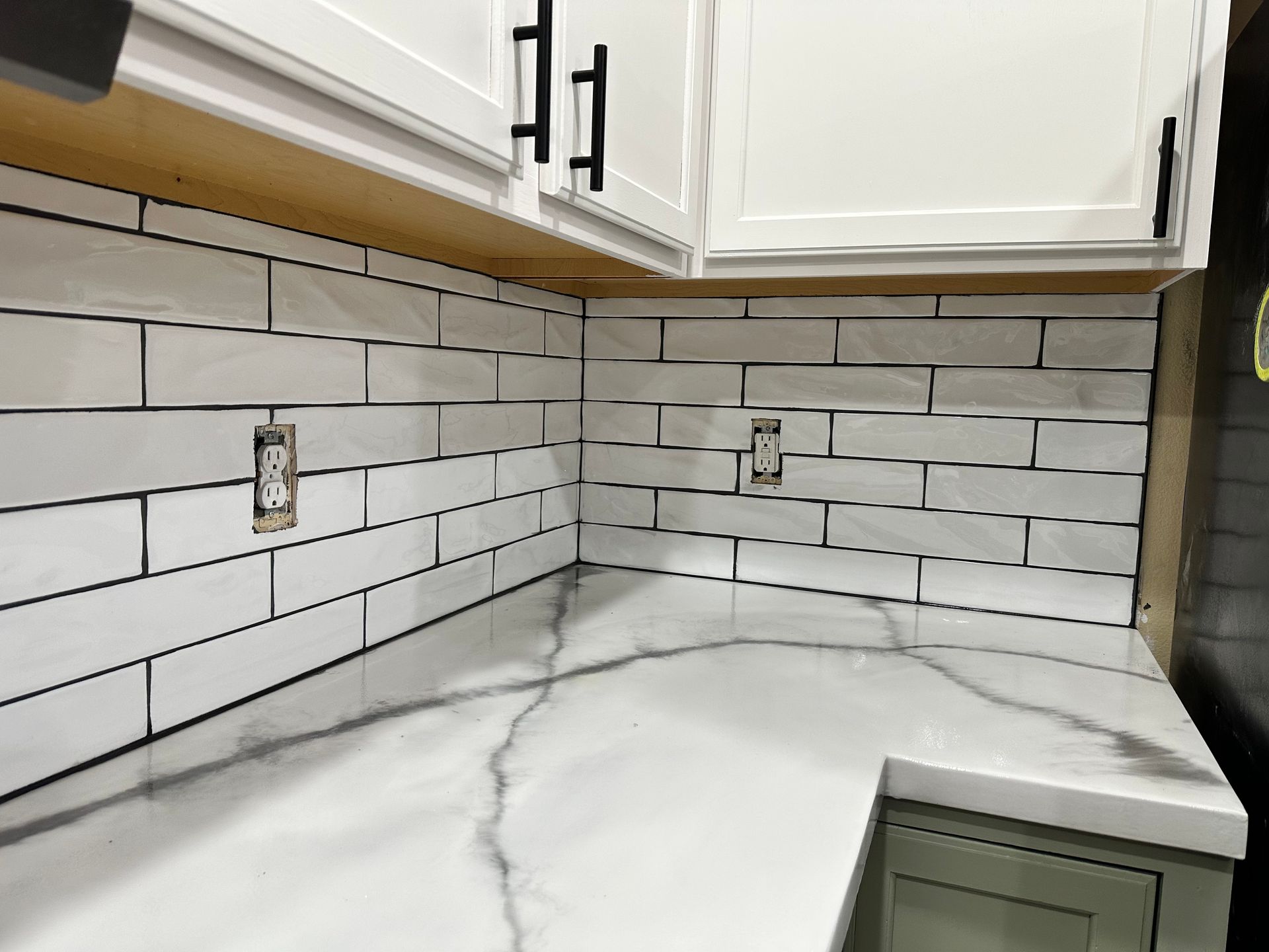 A kitchen with white cabinets , white counter tops , and white subway tiles.