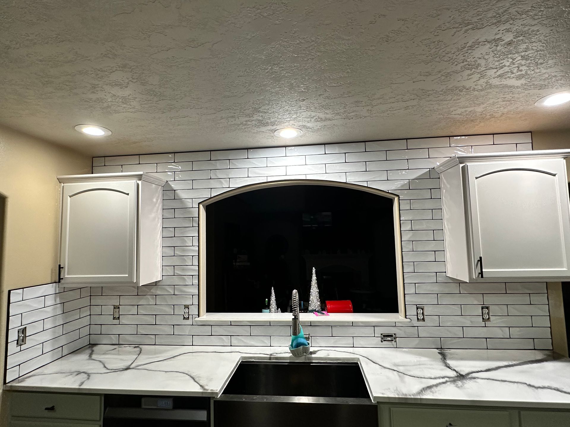 A kitchen with white cabinets and a stainless steel sink