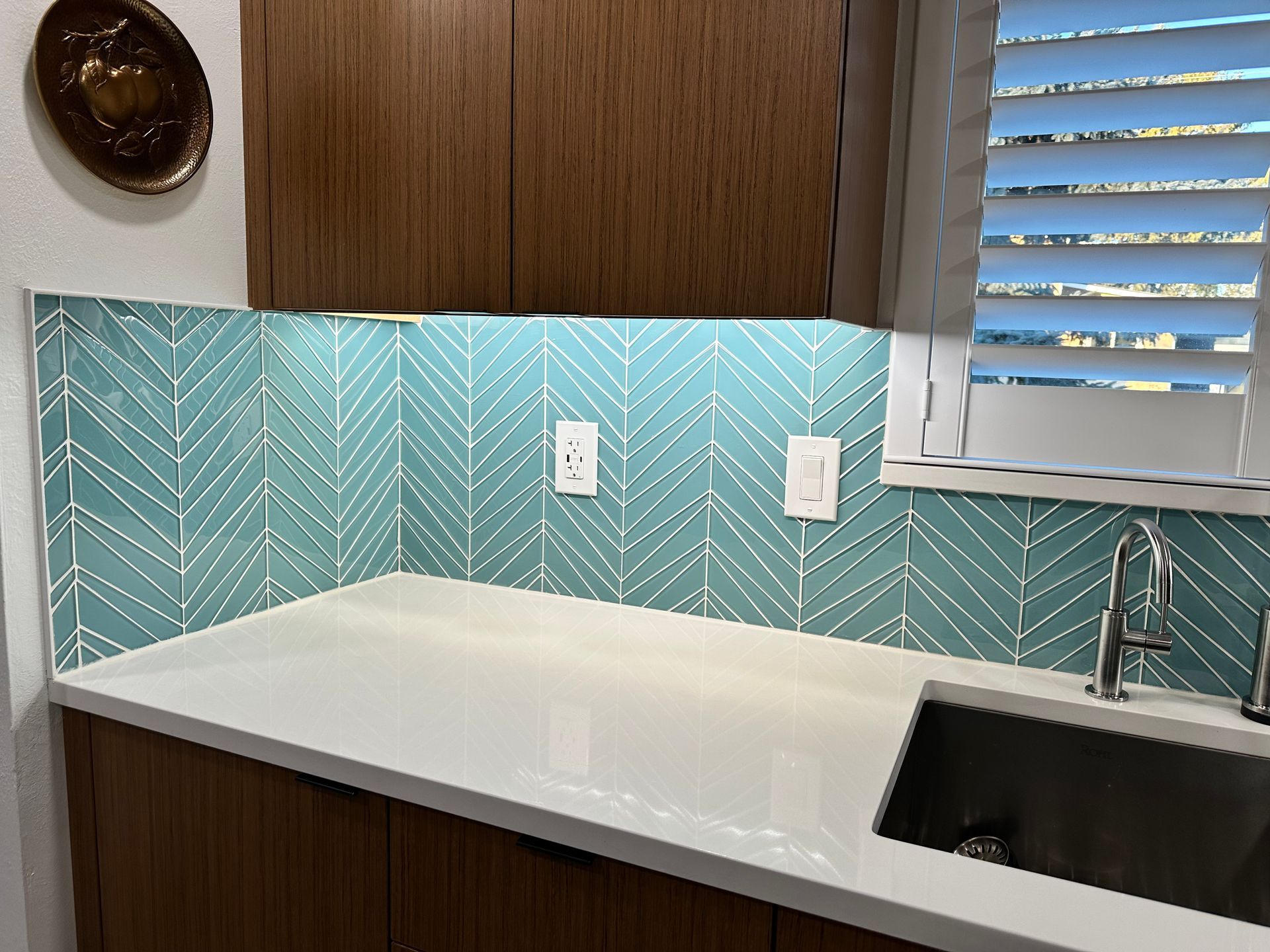 A kitchen with a sink and a window with shutters.