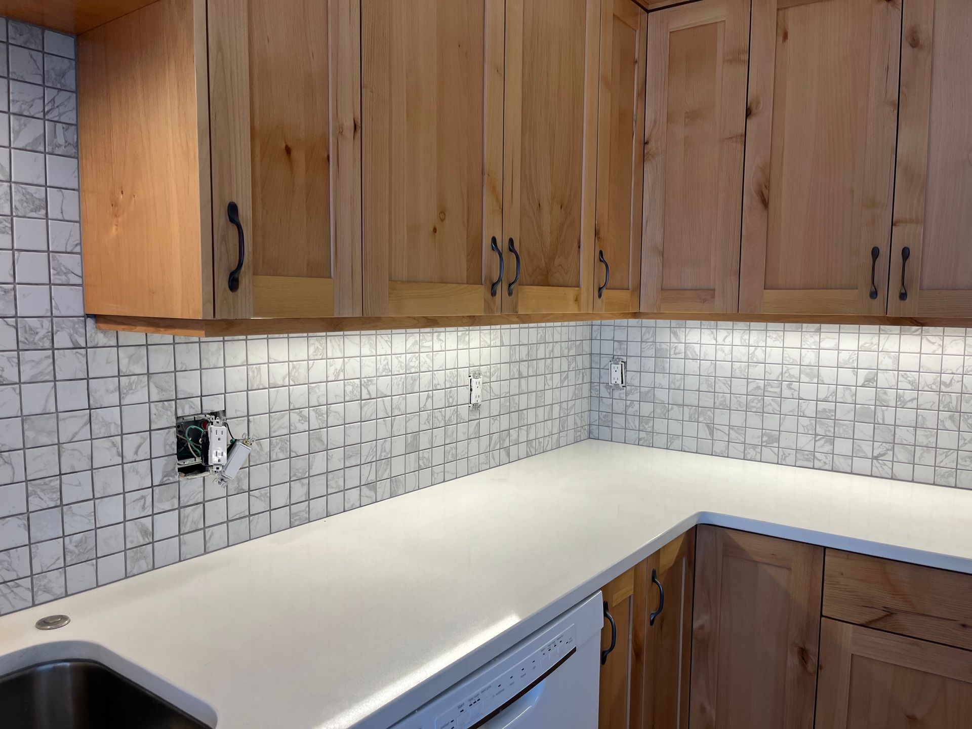 A kitchen with wooden cabinets and white counter tops