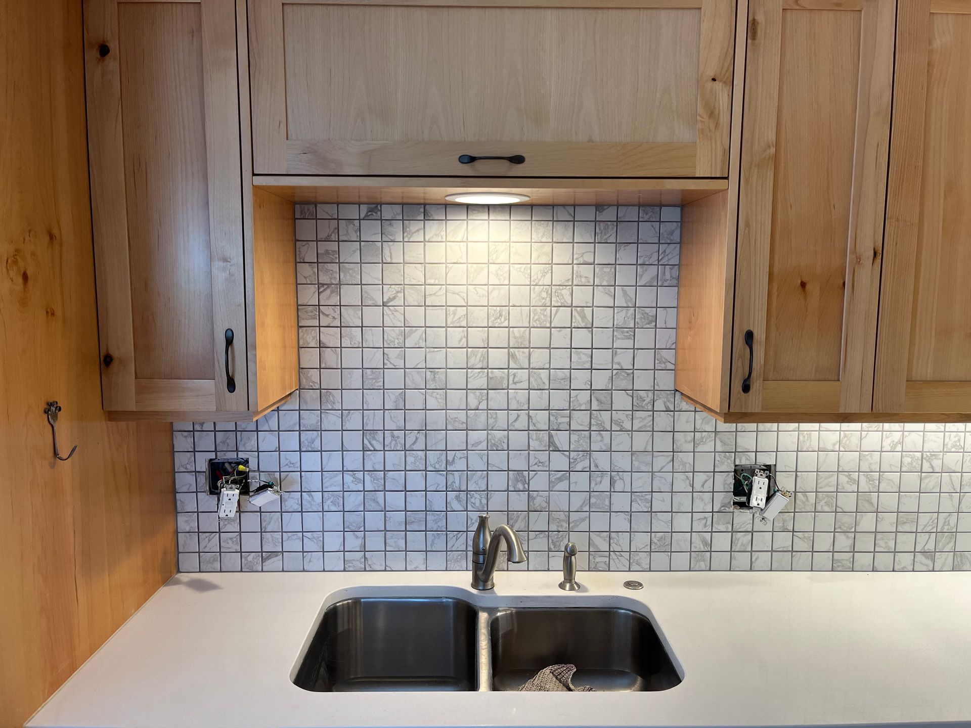 A kitchen with a double sink and wooden cabinets.