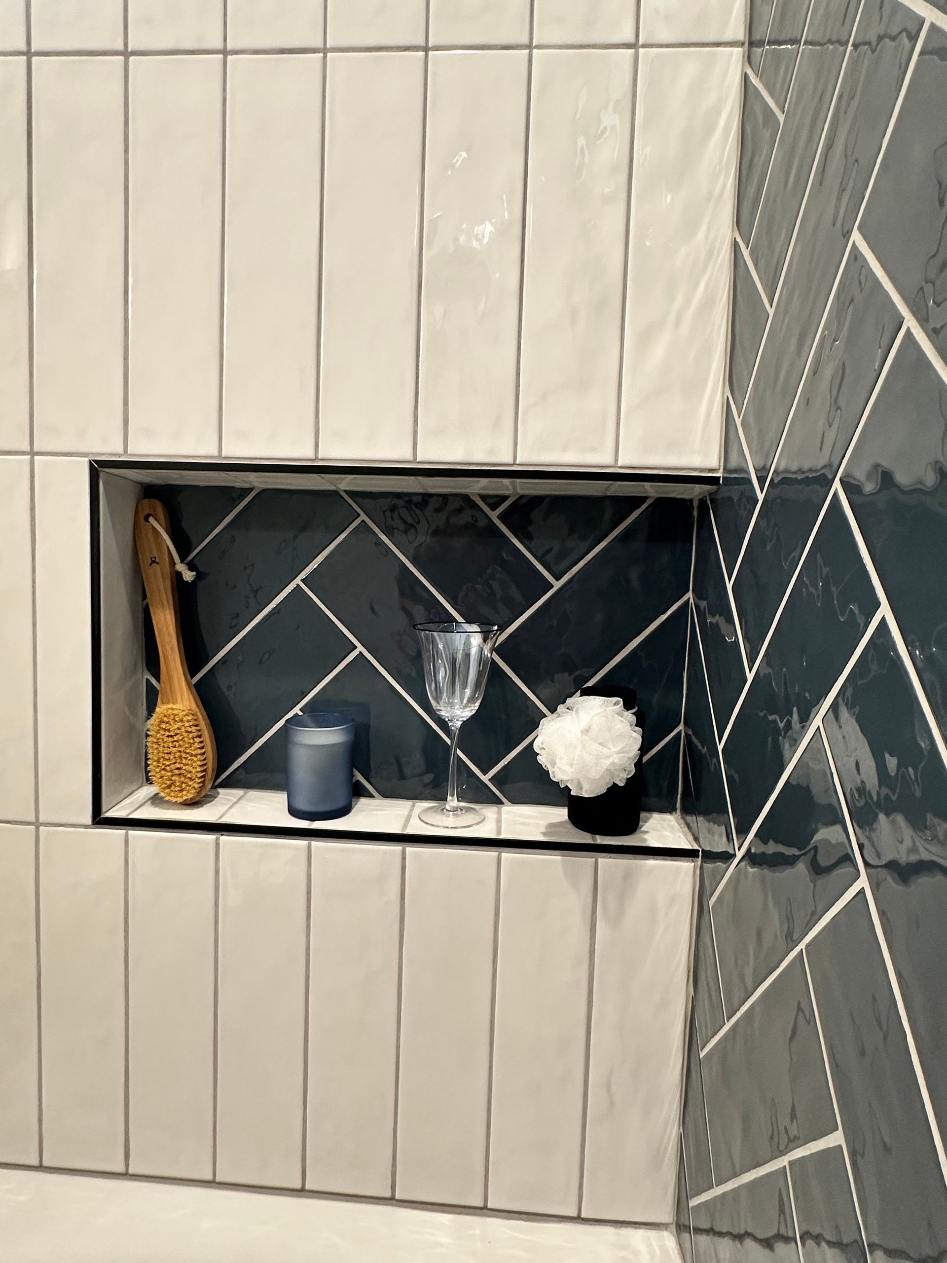 There is a shelf in the wall with a glass of wine and a candle.