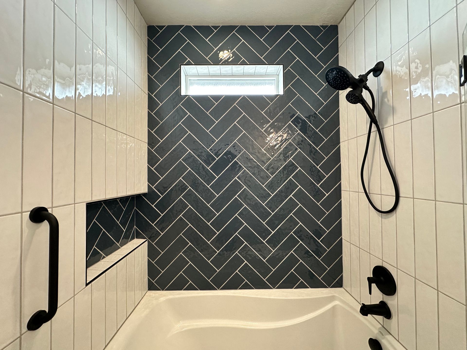A bathroom with black and white tiles and a bathtub.
