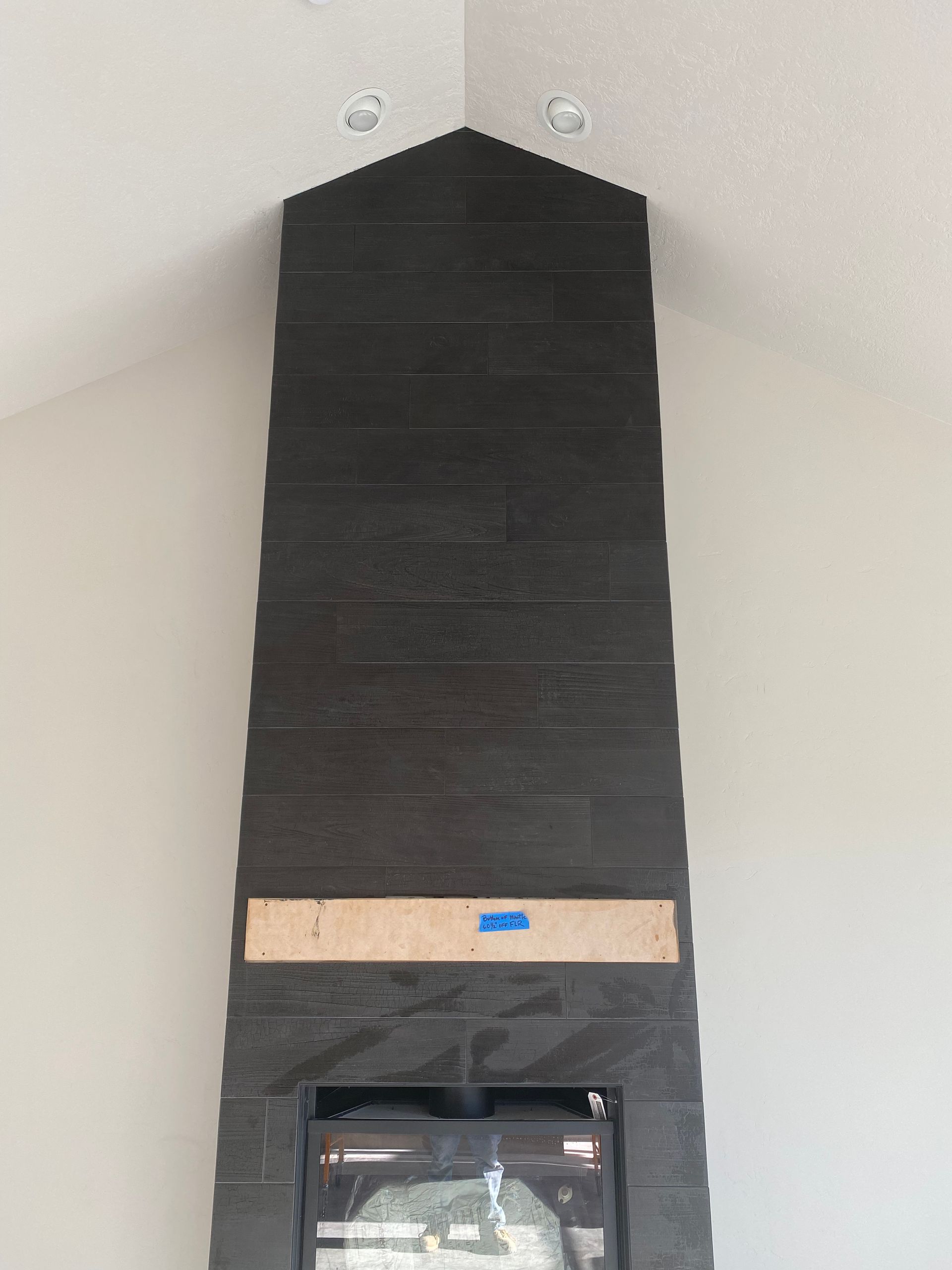 A black brick fireplace is being built in a living room.