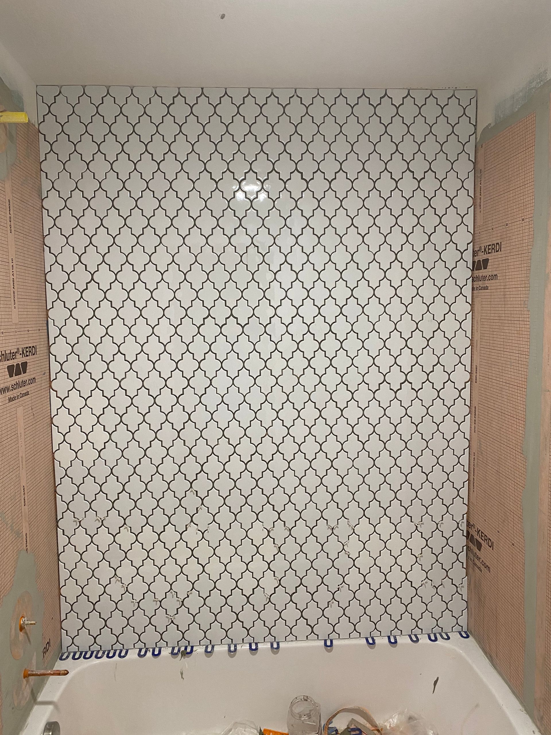 A bathroom with a bathtub and a wall with tiles on it.