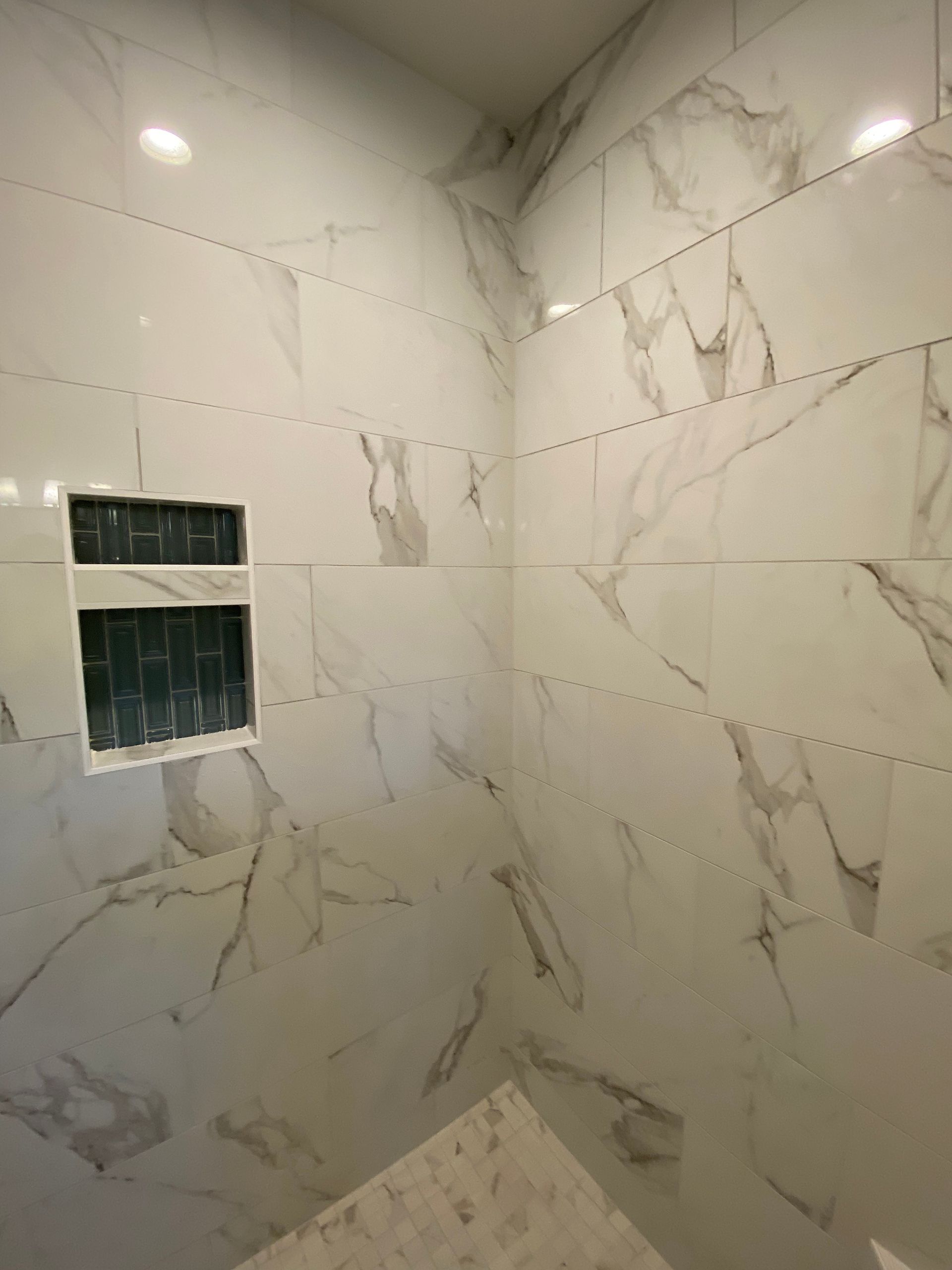 A bathroom with marble tiles and a shower stall.