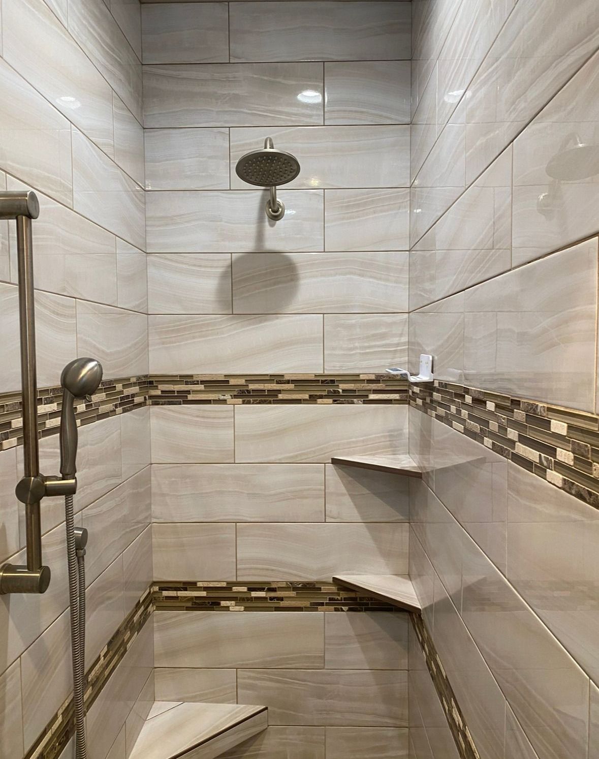 A shower with a shower head and shelves in a bathroom.