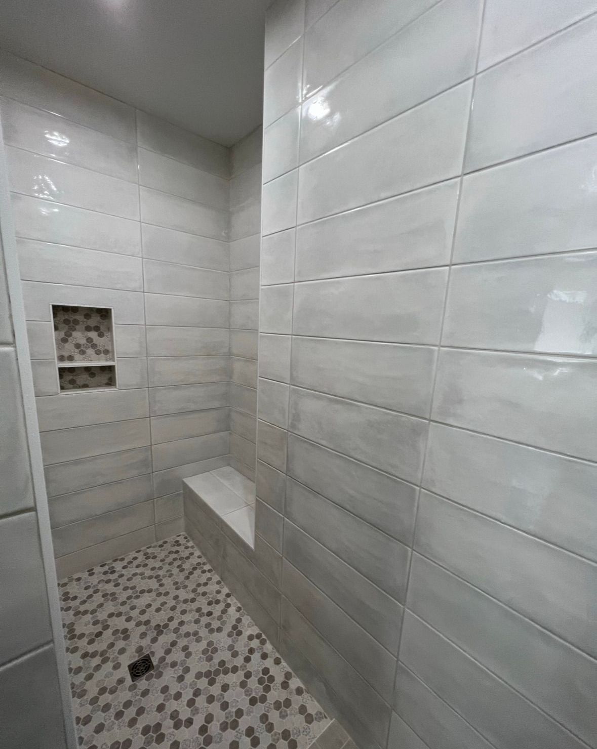 A bathroom with white tiles and a walk in shower.