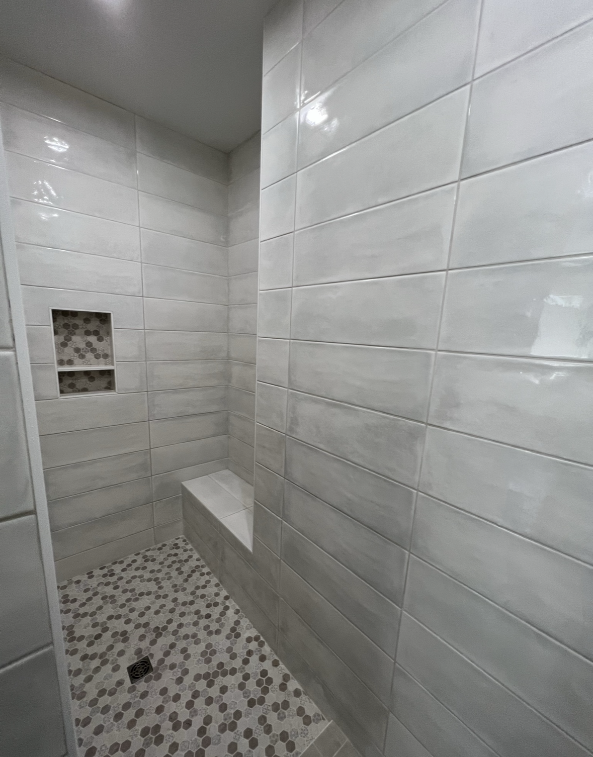 A bathroom with white tiles and a walk in shower.