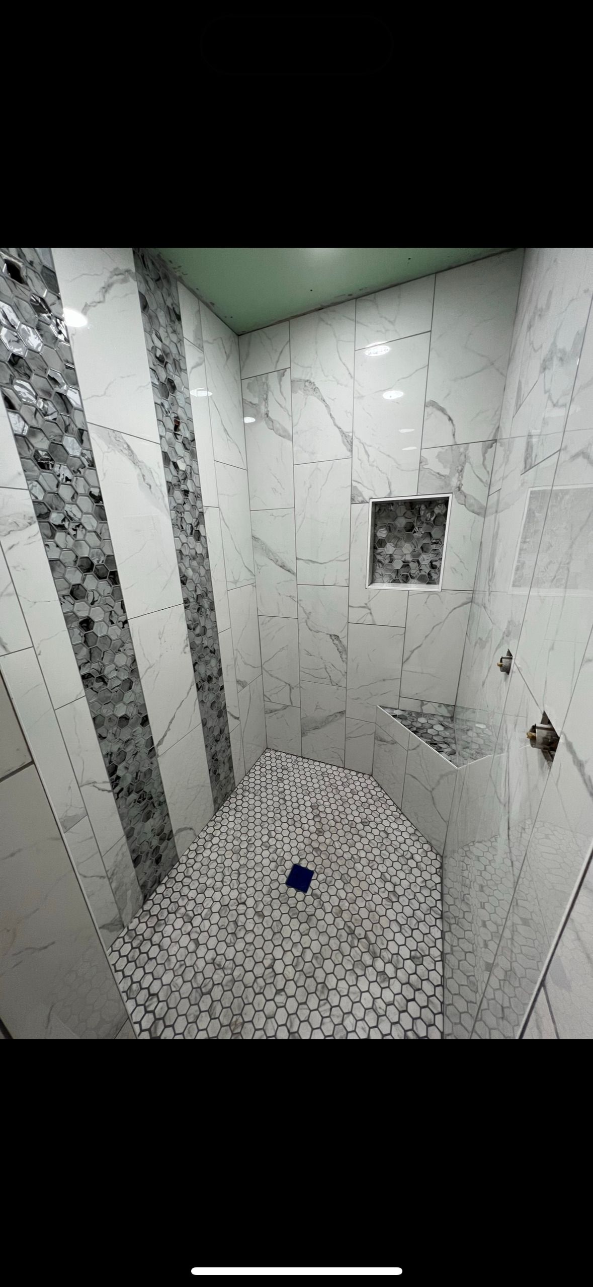 A bathroom with marble tiles and a walk in shower.