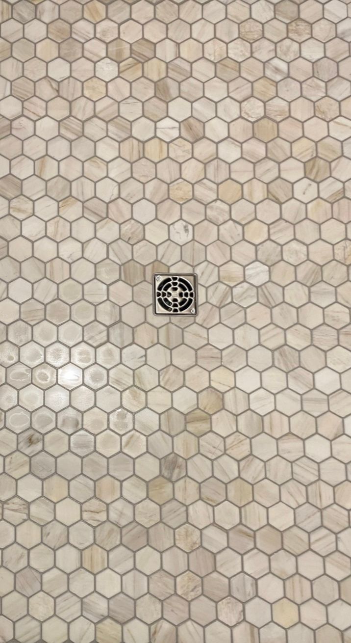 A shower floor with a drain in the middle of it.