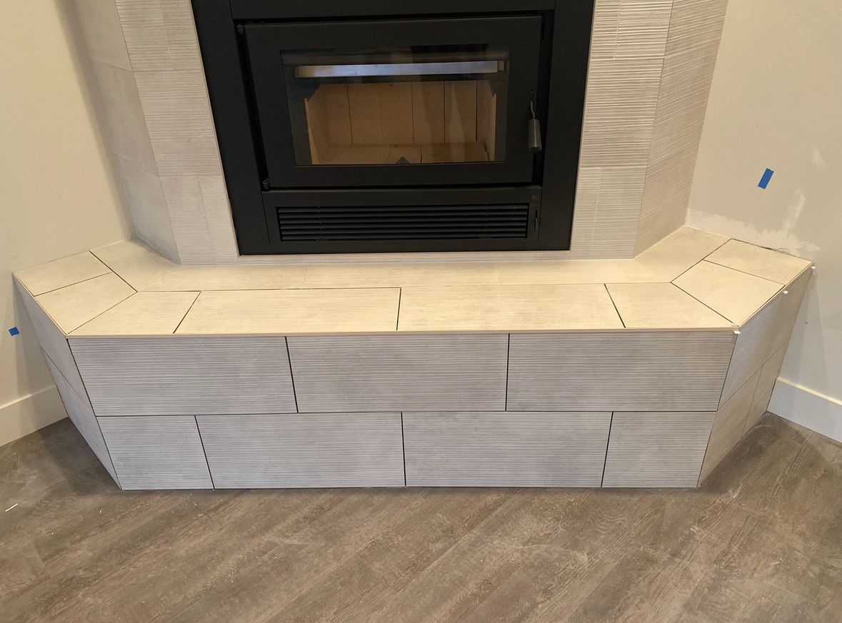 A fireplace with a bench underneath it in a living room.