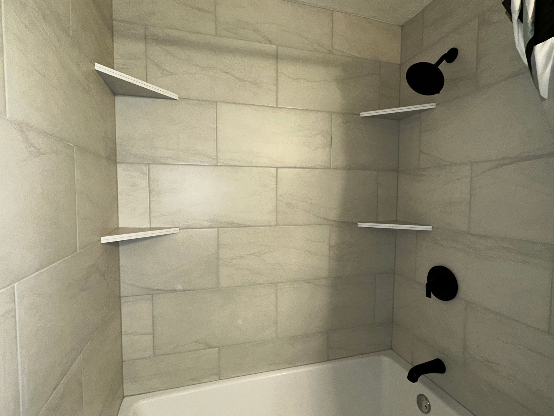 A bathroom with a bathtub , shower , and shelves.