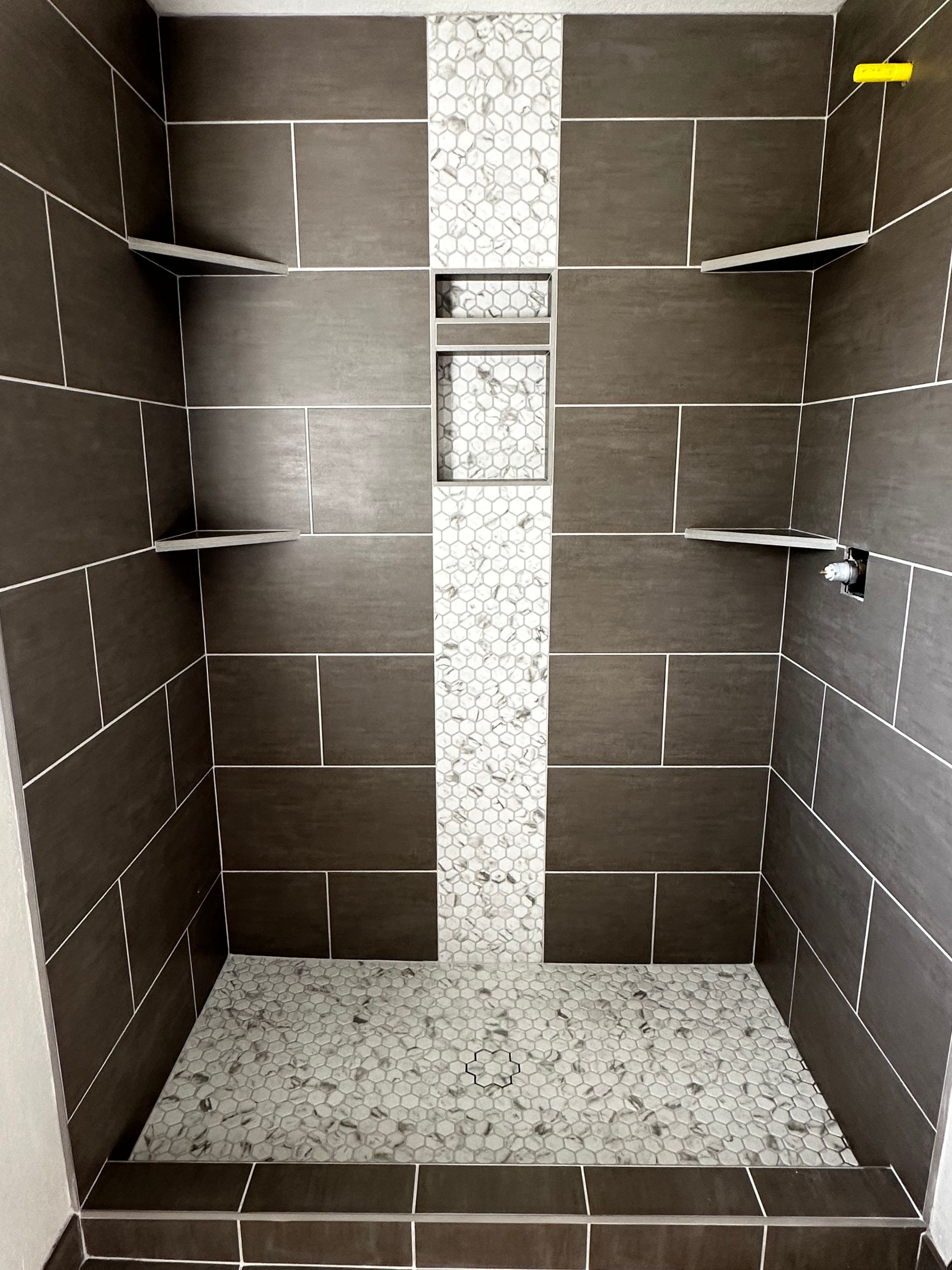 A walk in shower with brown and white tiles