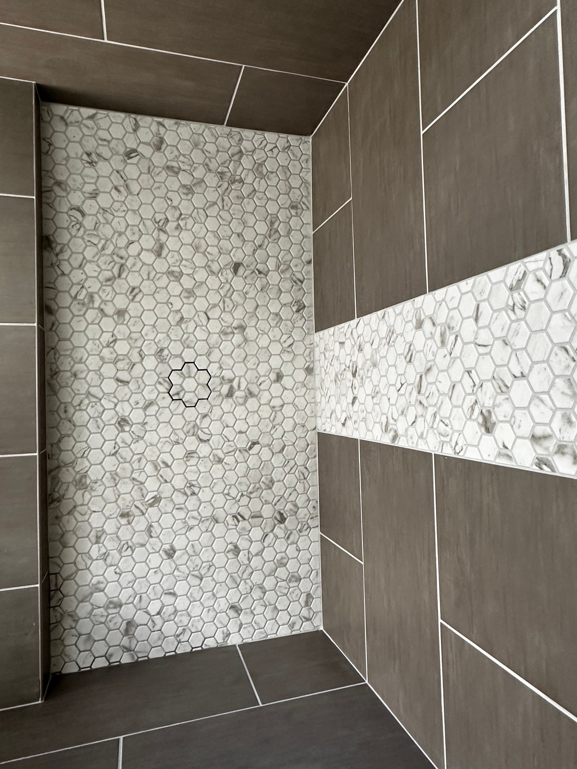 A bathroom with a walk in shower with marble tiles on the wall.