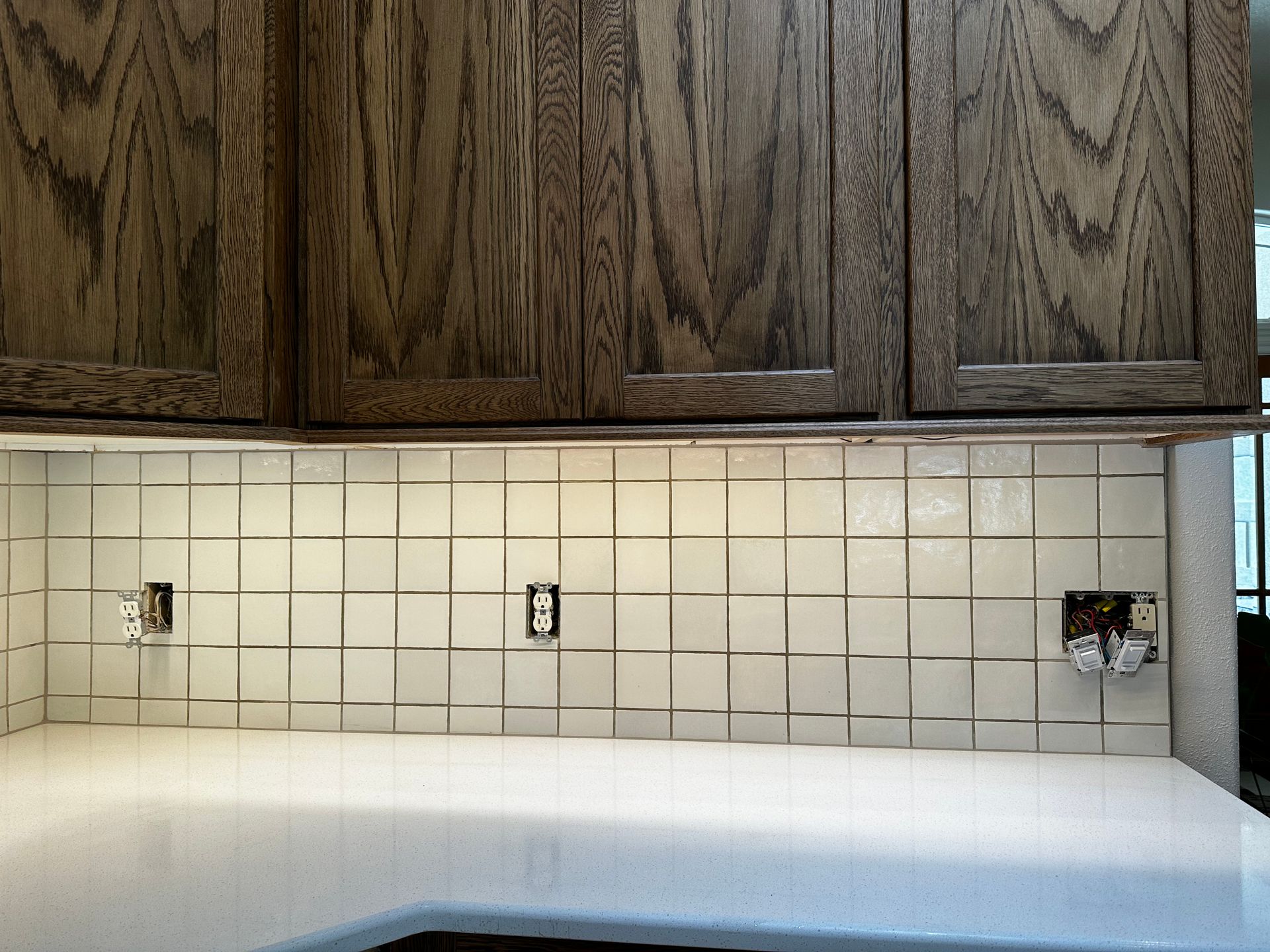 A kitchen with white tiles and wooden cabinets