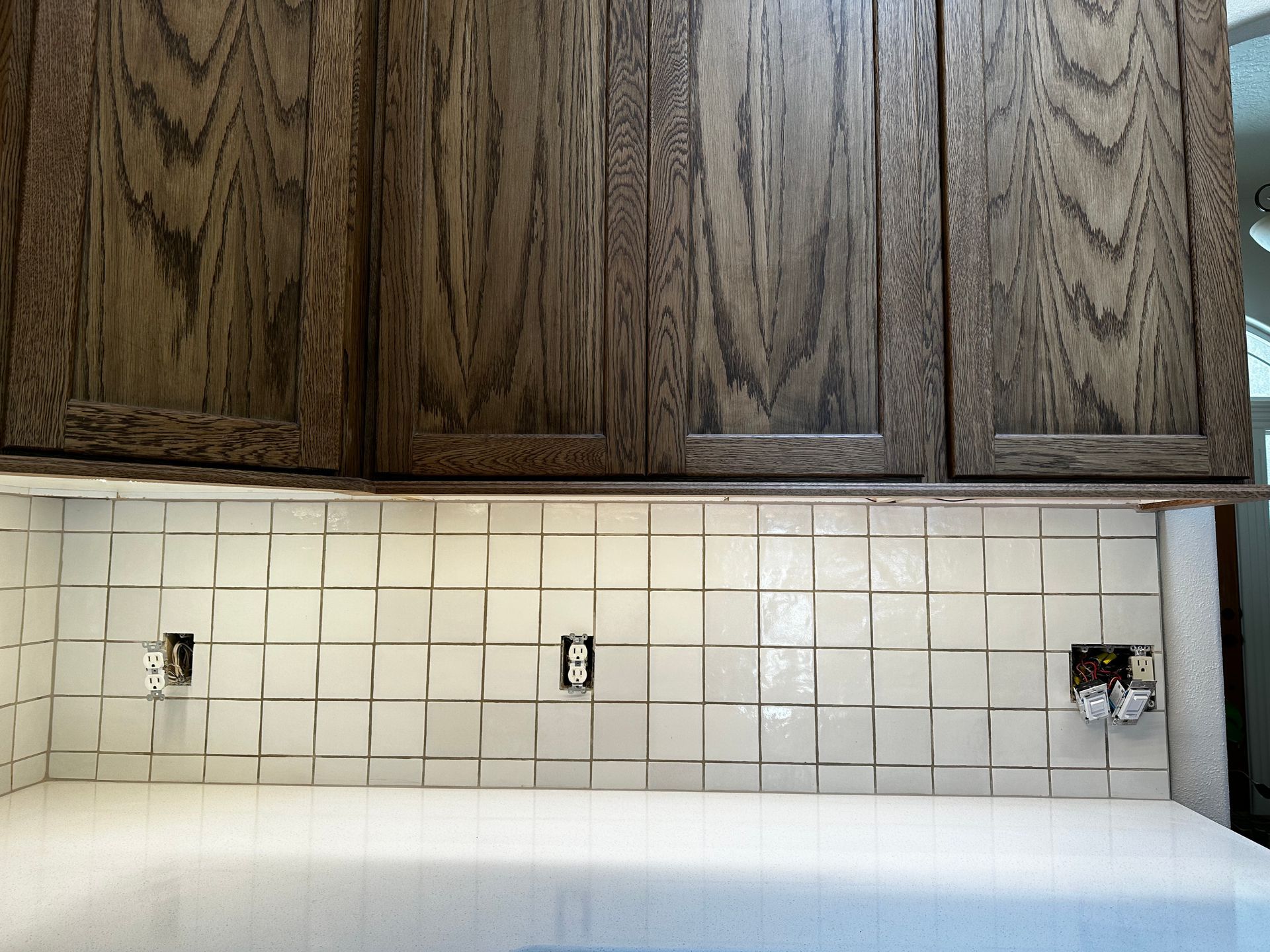 A kitchen with white tiles and wooden cabinets