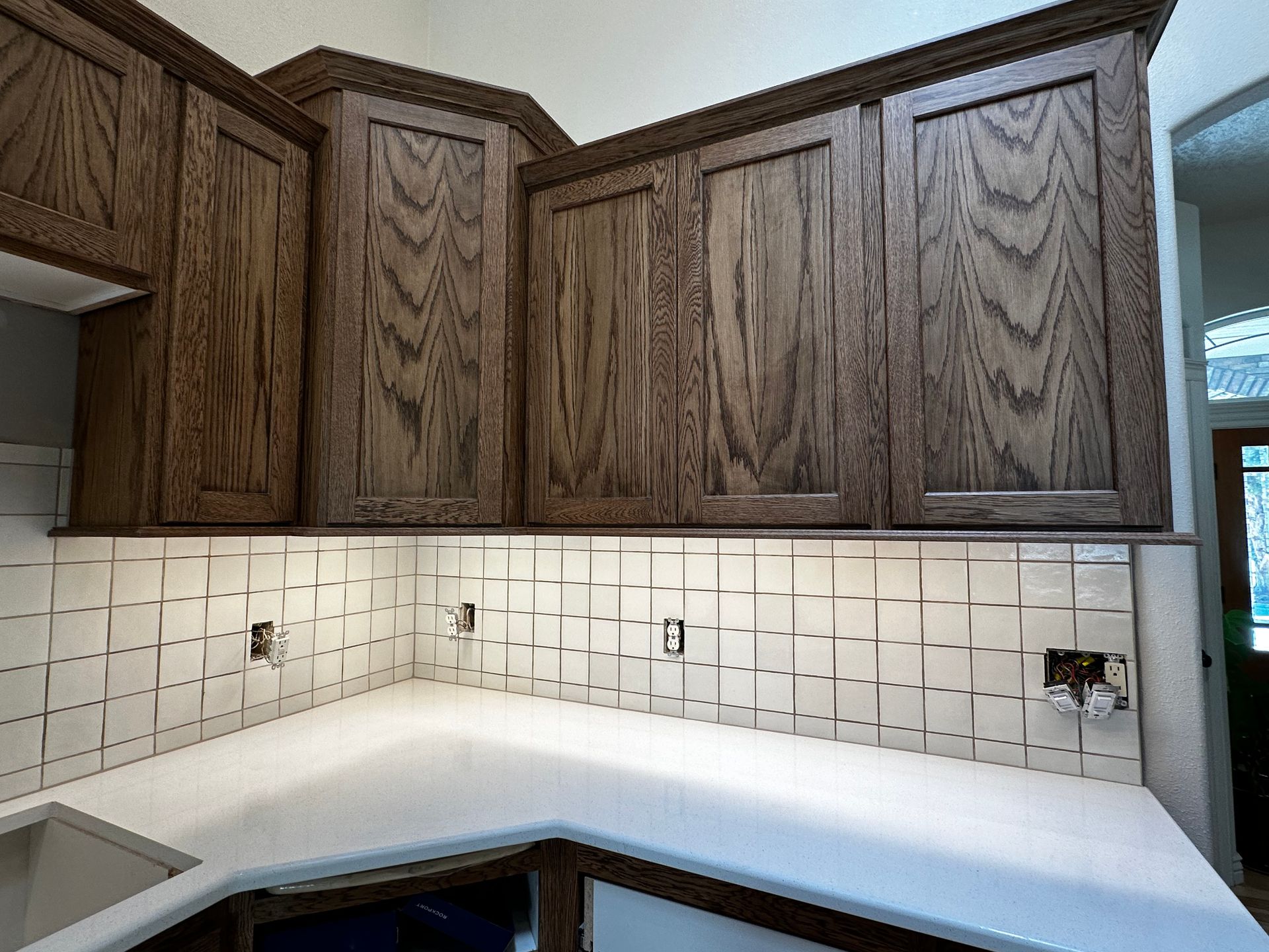 A kitchen with wooden cabinets and white counter tops