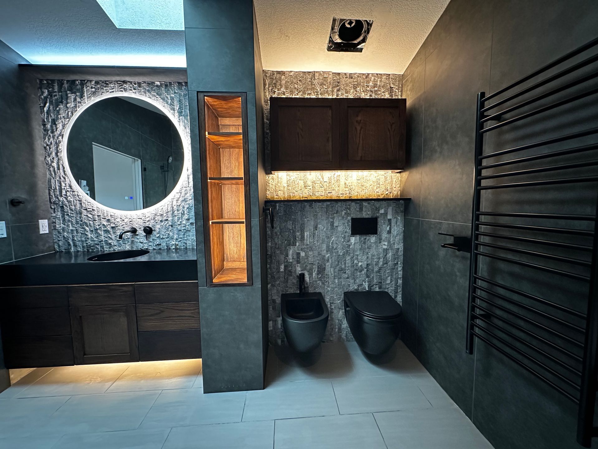 A bathroom with two toilets , a sink and a mirror.