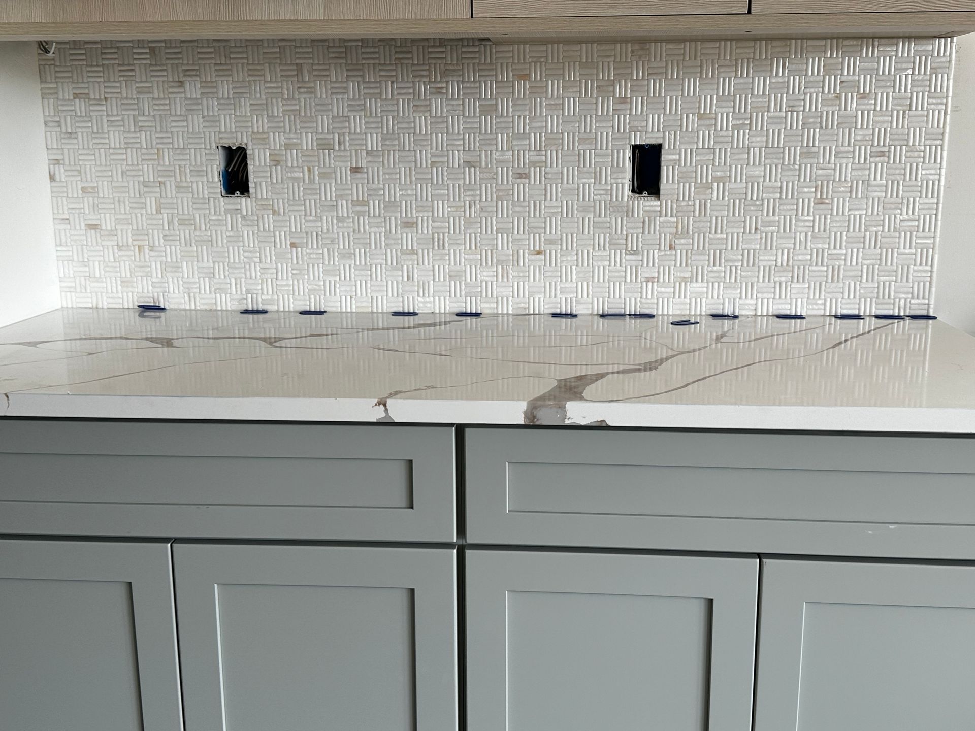 A kitchen with gray cabinets and a white counter top.