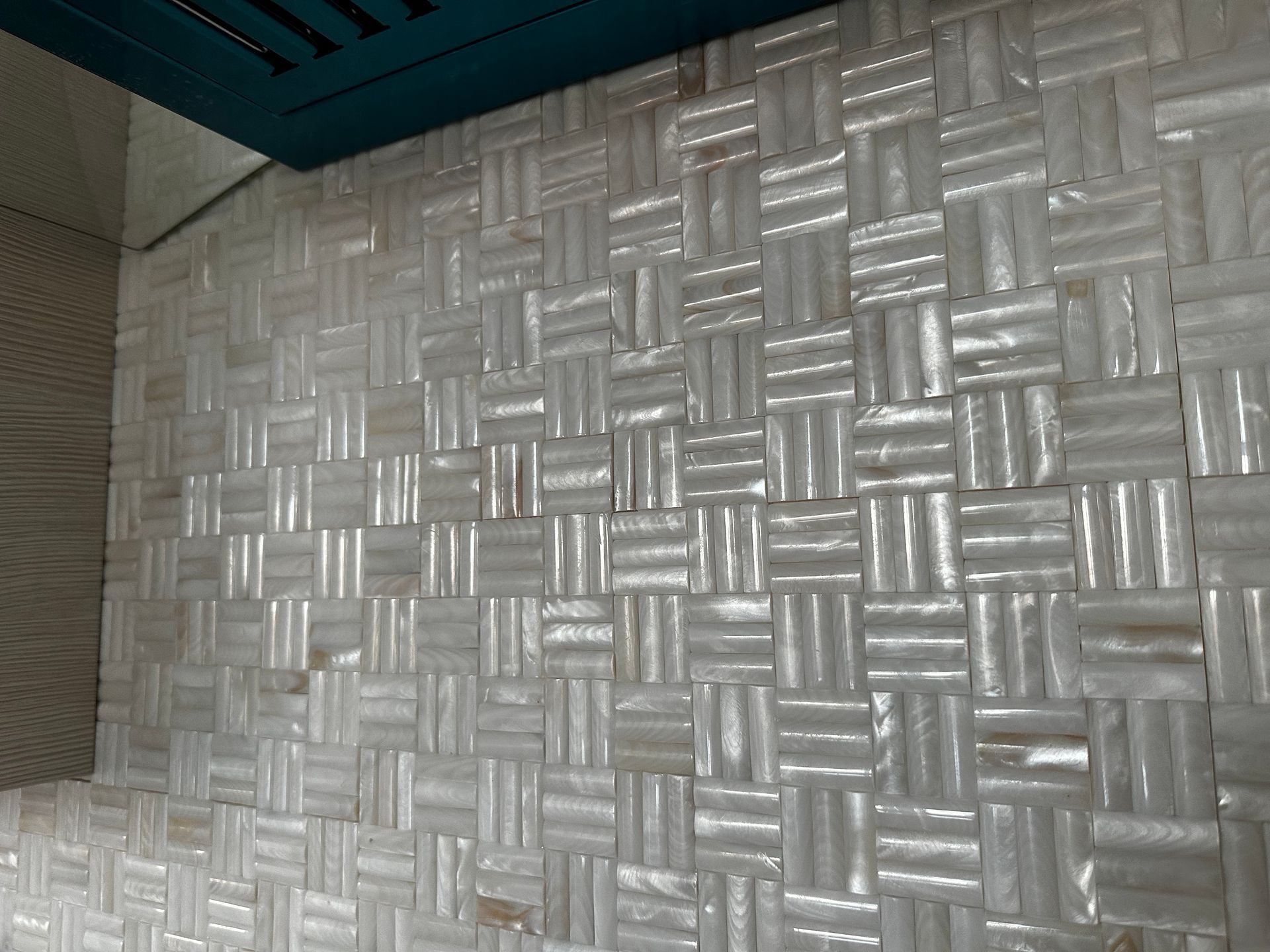 A close up of a white tile wall with a woven pattern.