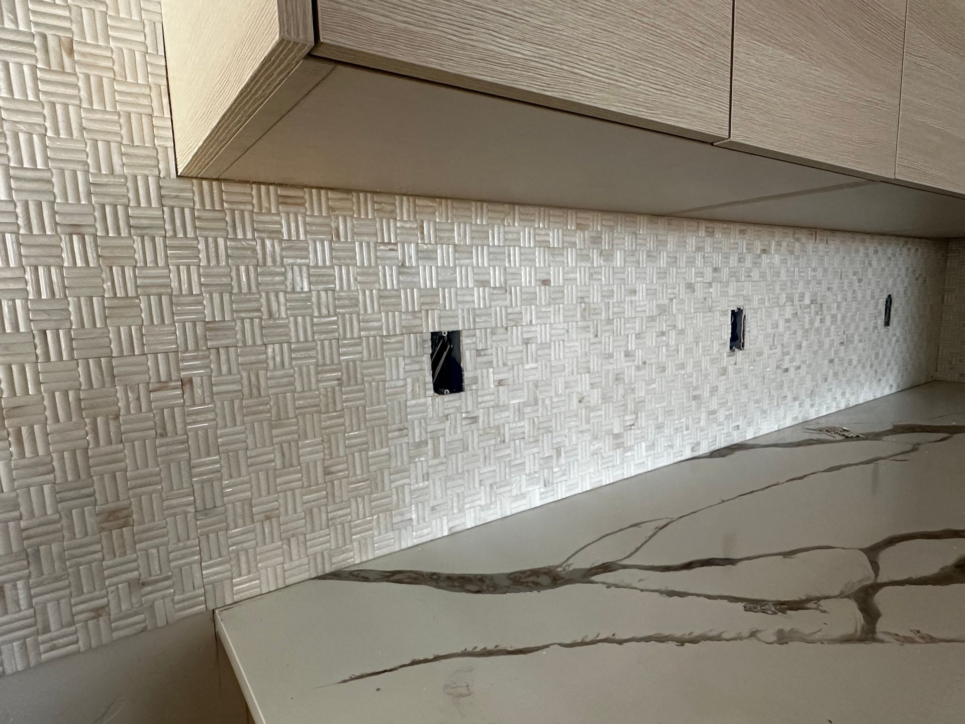 A kitchen with a white tile backsplash and a white counter top.