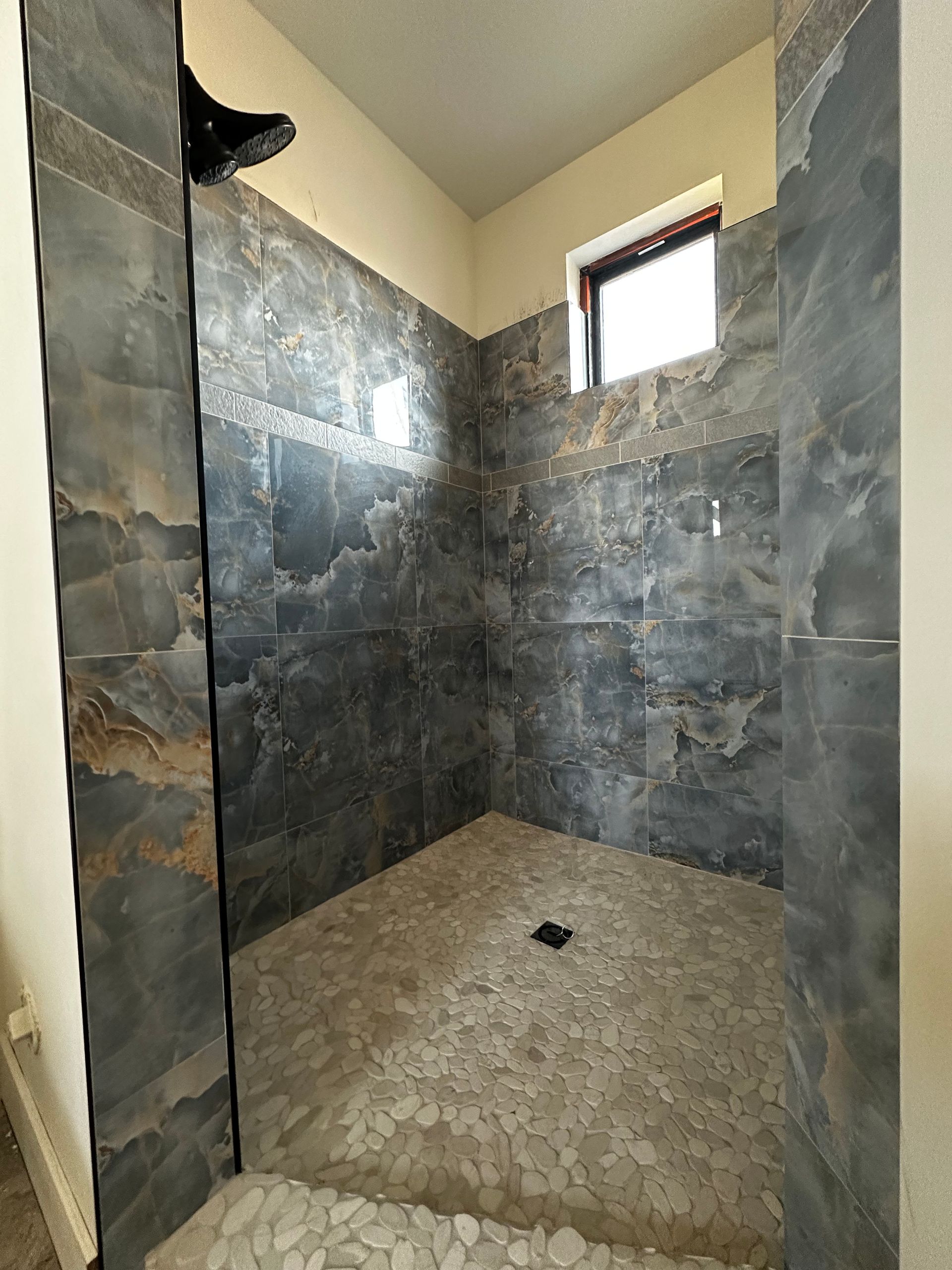 A bathroom with a walk in shower and a window.