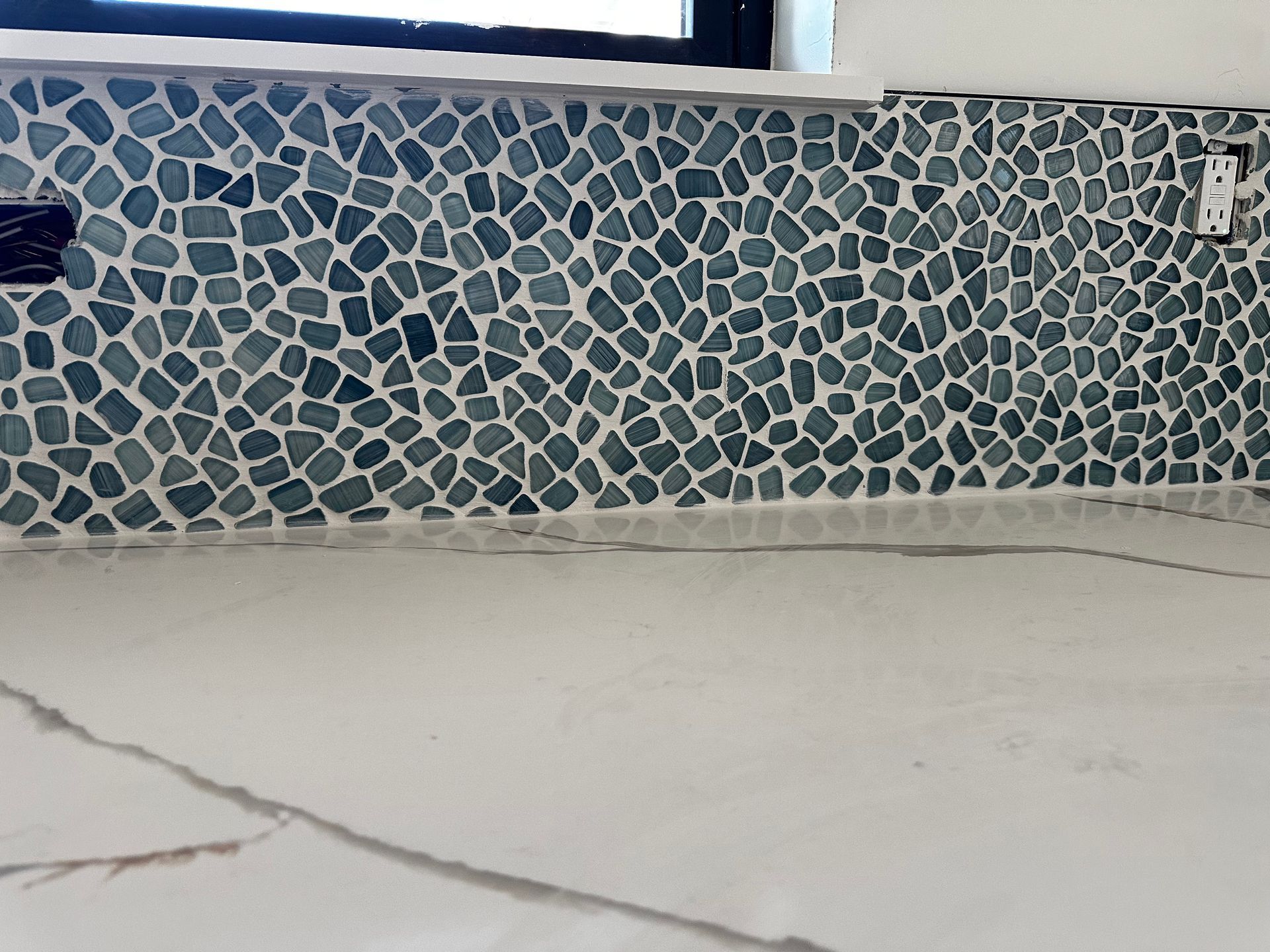 A tiled wall with a window in the background